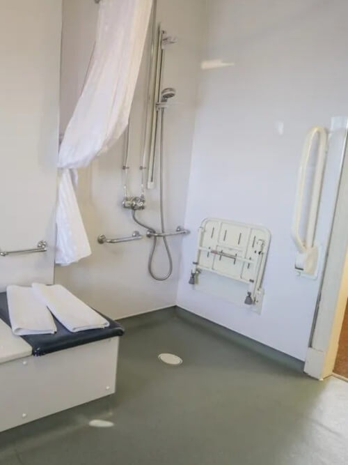 Wet room with wall‑mounted shower seat, grab bars Wet room with wall‑mounted shower seat, grab bars