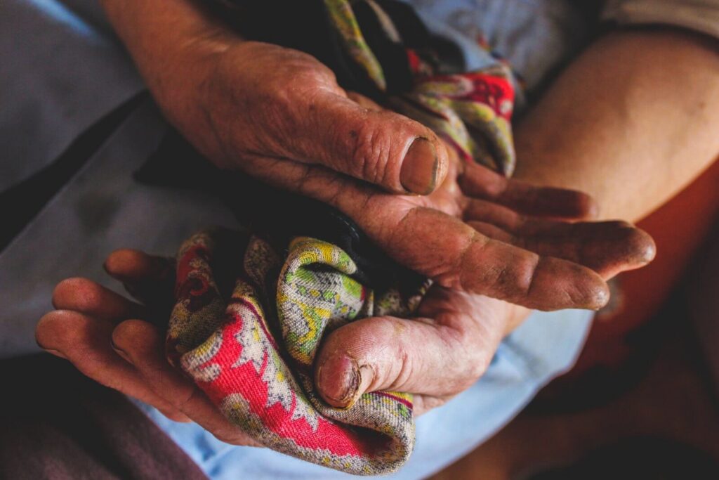 Weathered hands of an elderly woman holding a cotton scarf