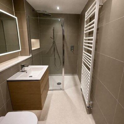 modern-neutral-green-shower-room Sage green shower room with tile-effect boards, accessible shower and anti-slip flooring
